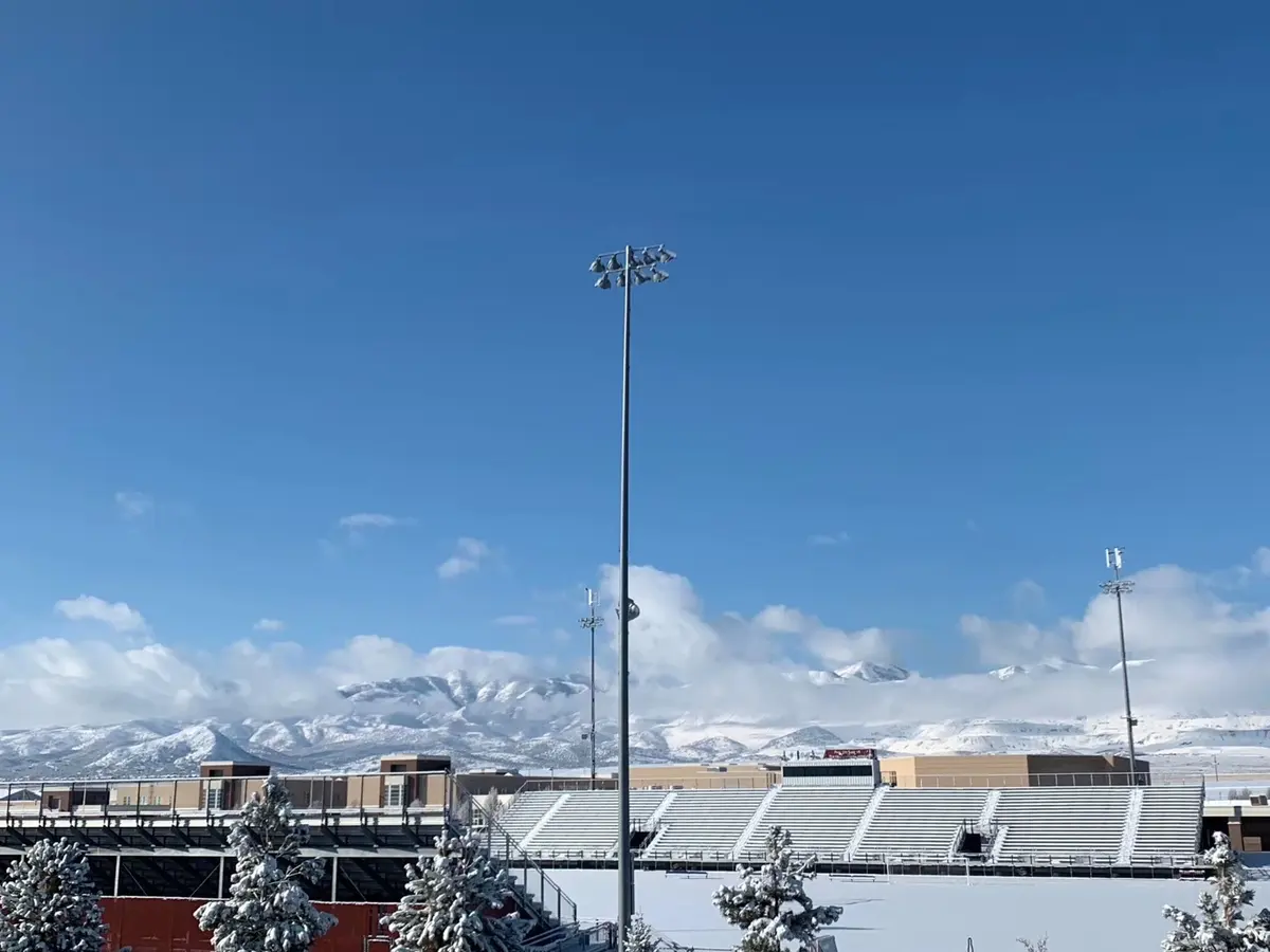 美国学校体育场灯柱、积雪山脉与蓝天