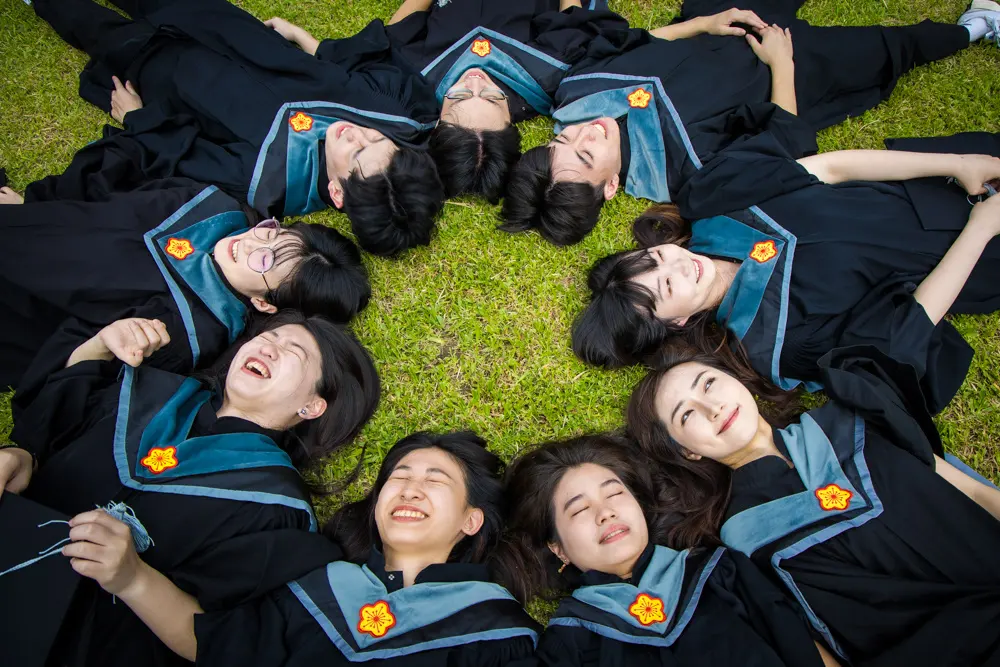 学生穿毕业服在草坪上围成圆形创意合影