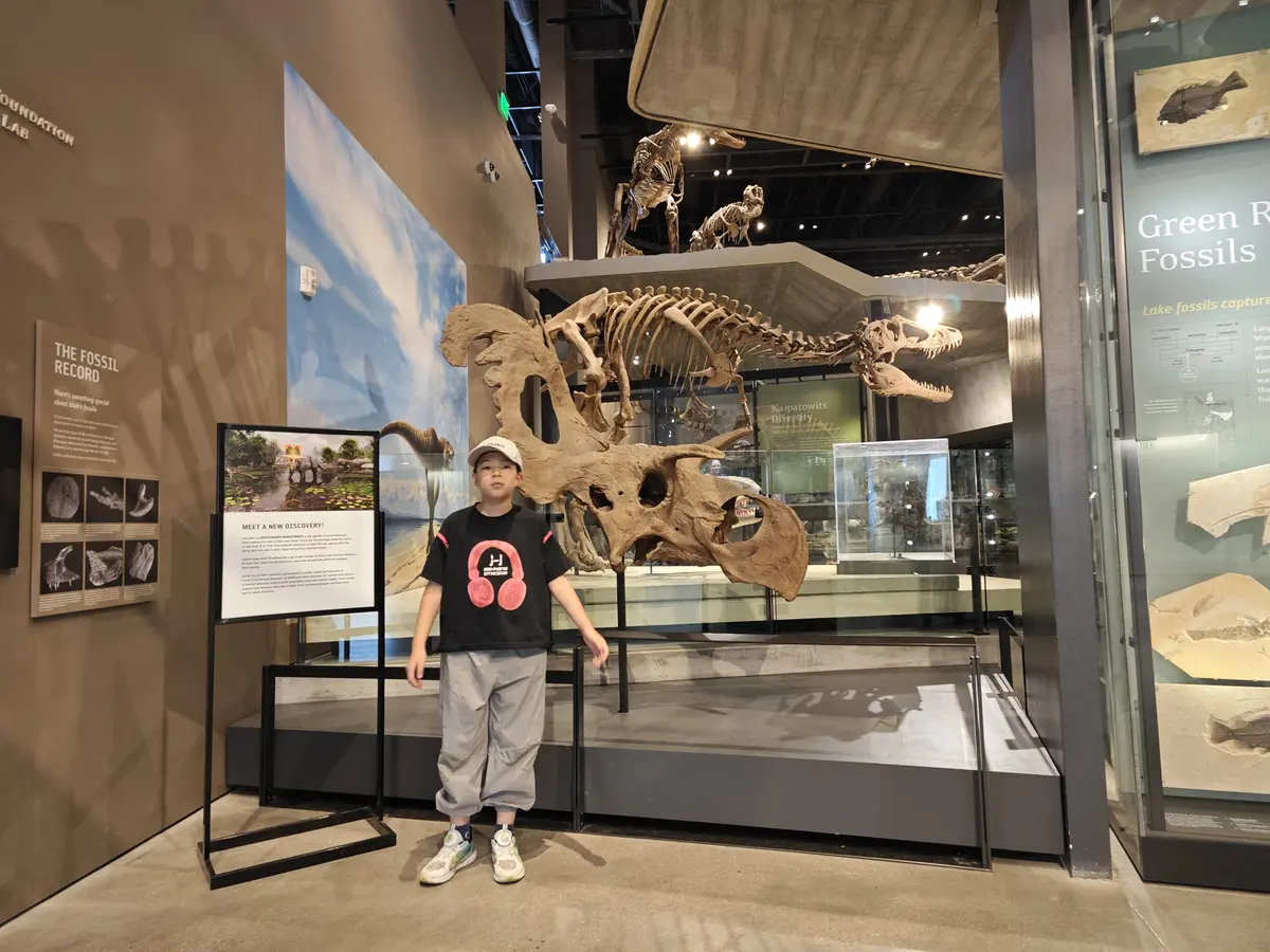学生在自然历史博物馆恐龙化石展区留影