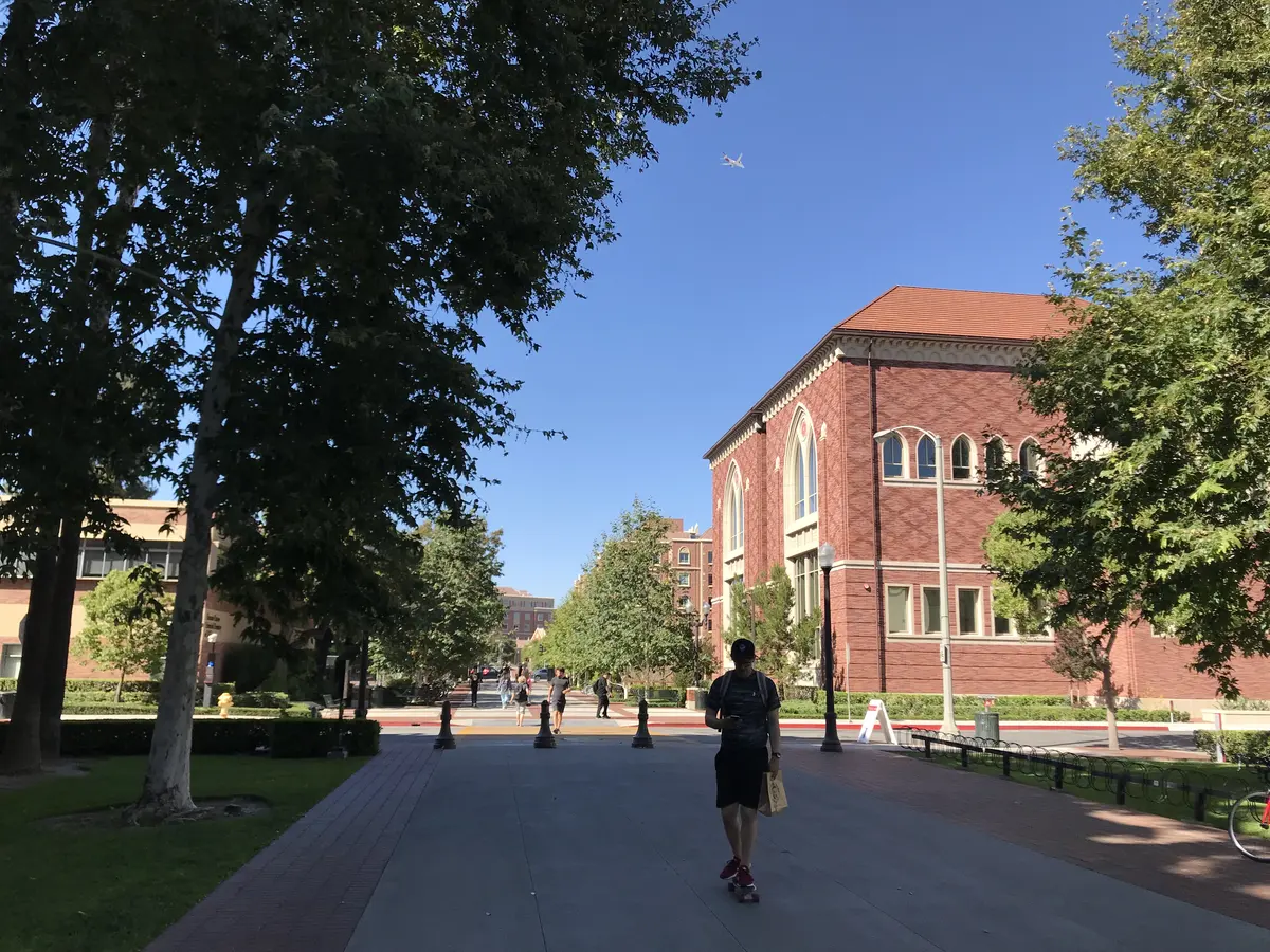 学生行走在美国大学红砖教学楼与林荫校园之间