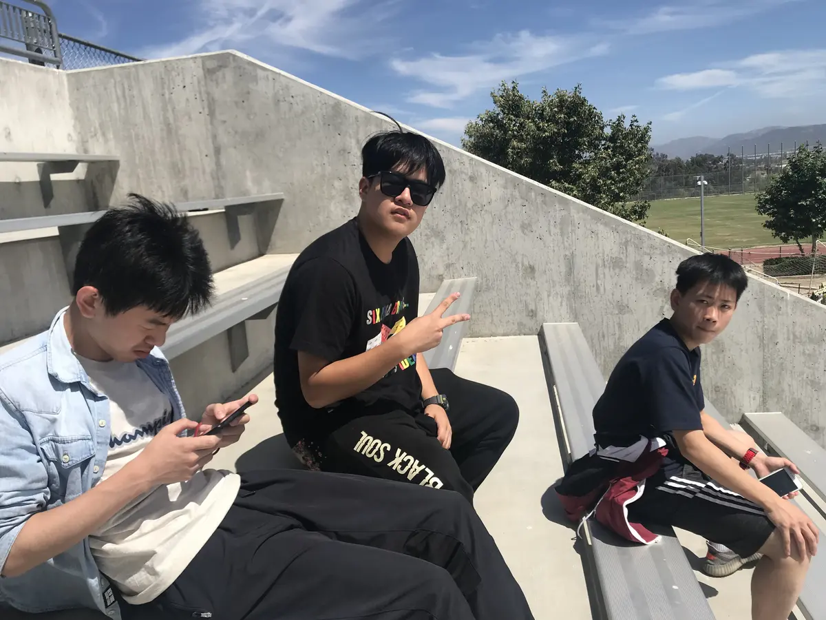 中国学生在美国学校体育场看台休息与交流