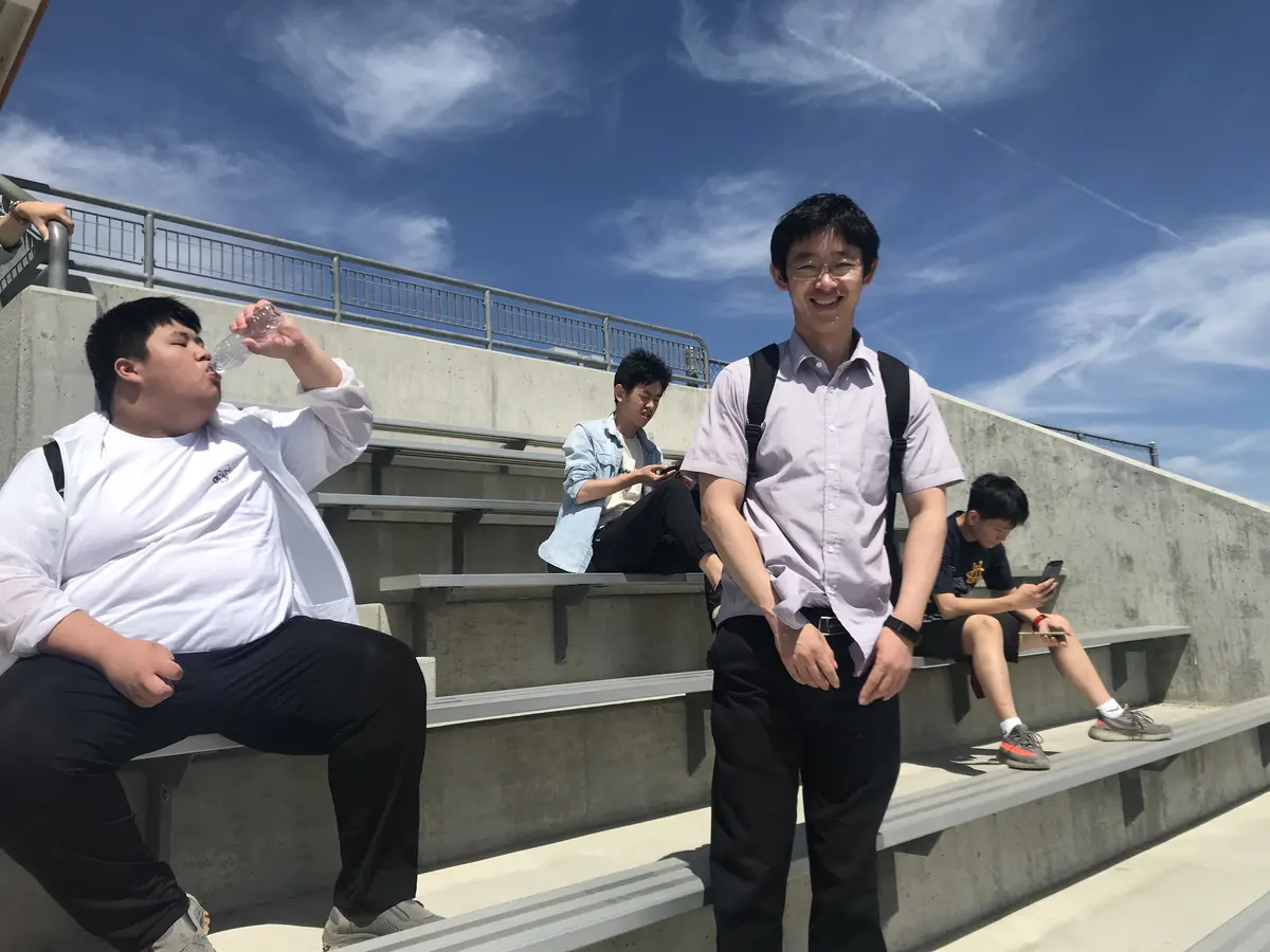 中国学生在美国学校体育场看台休息并交流