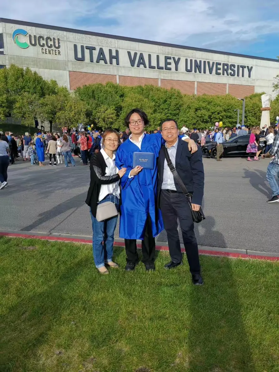 中国学生穿毕业服与家人在美国学校毕业典礼后合影