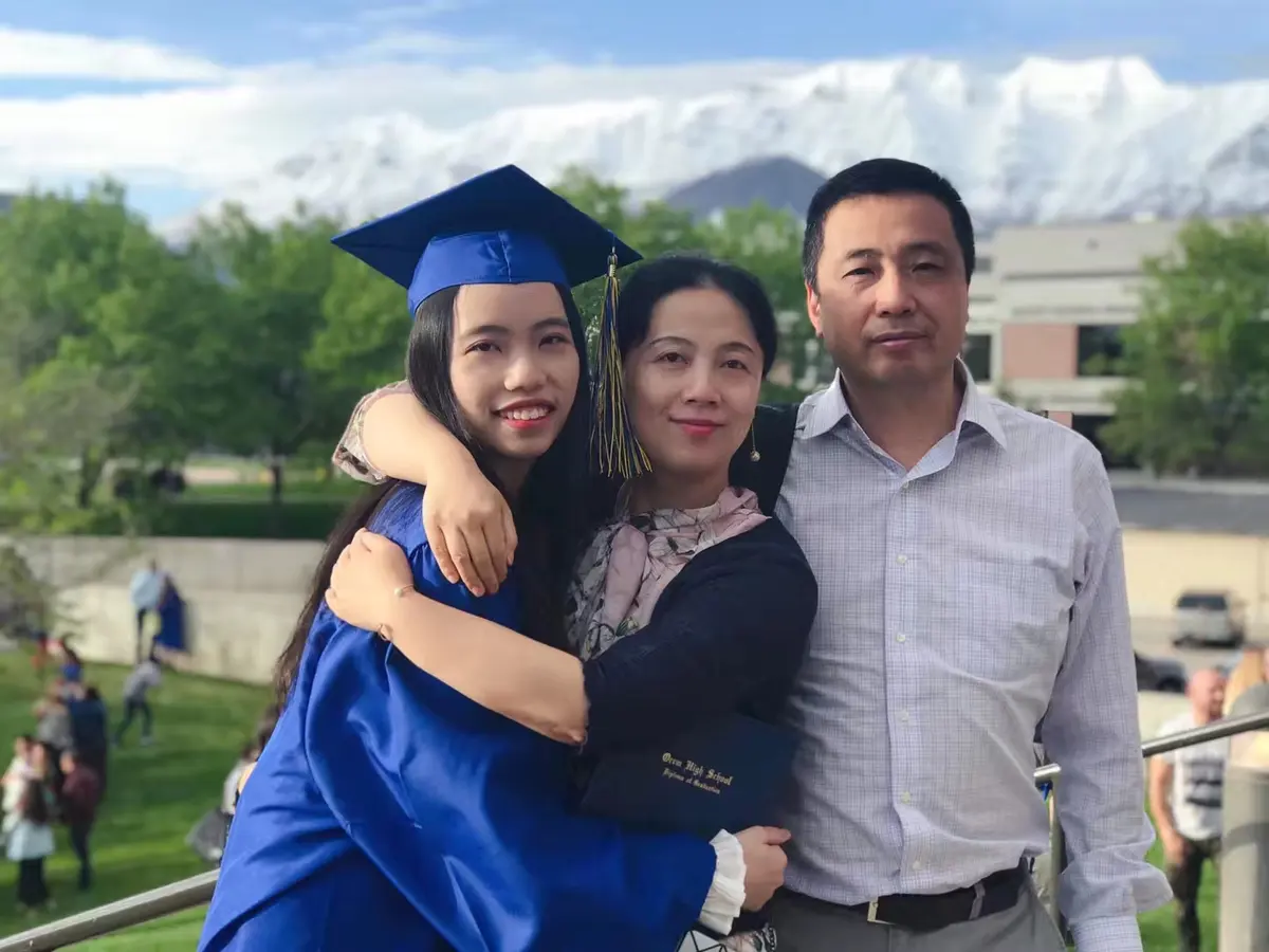 中国学生穿毕业服与家人在美国学校毕业典礼后合影