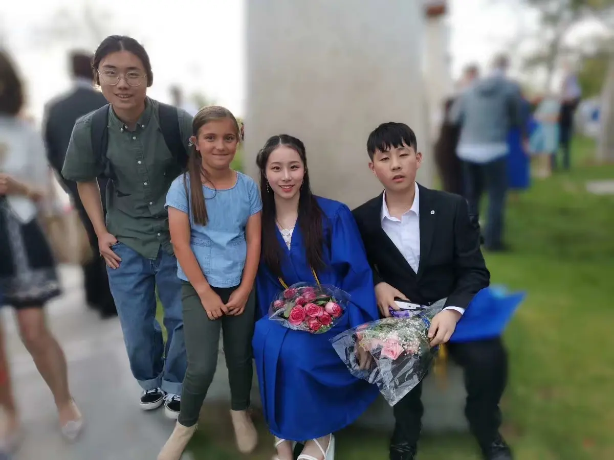 中国学生穿毕业服与家人或教师在毕业典礼后合影