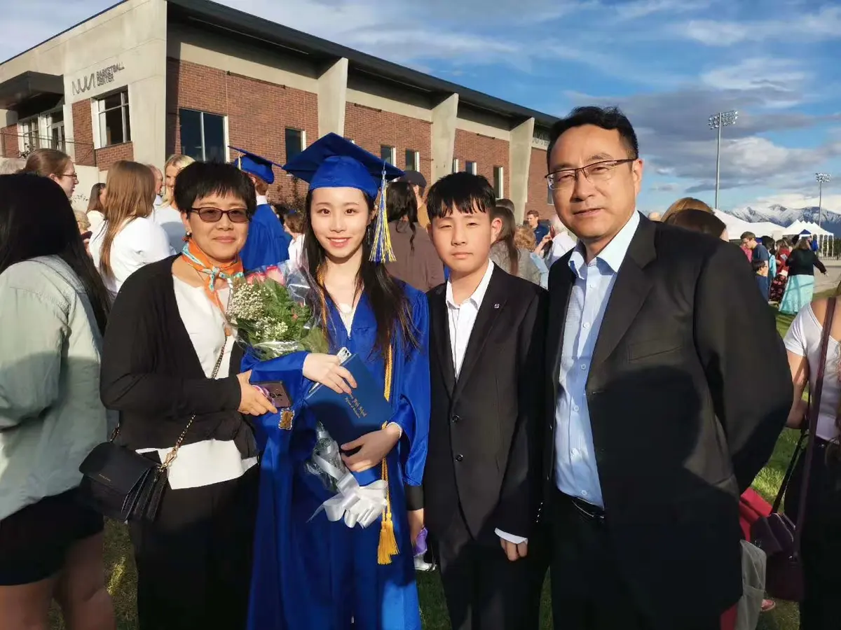 中国学生穿毕业服与家人或教师在毕业典礼后合影