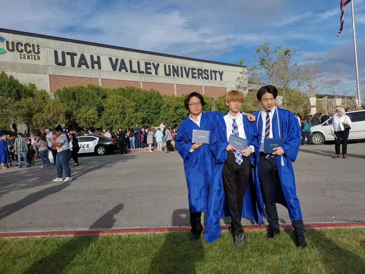 中国学生穿毕业服在犹他谷大学校牌前合影
