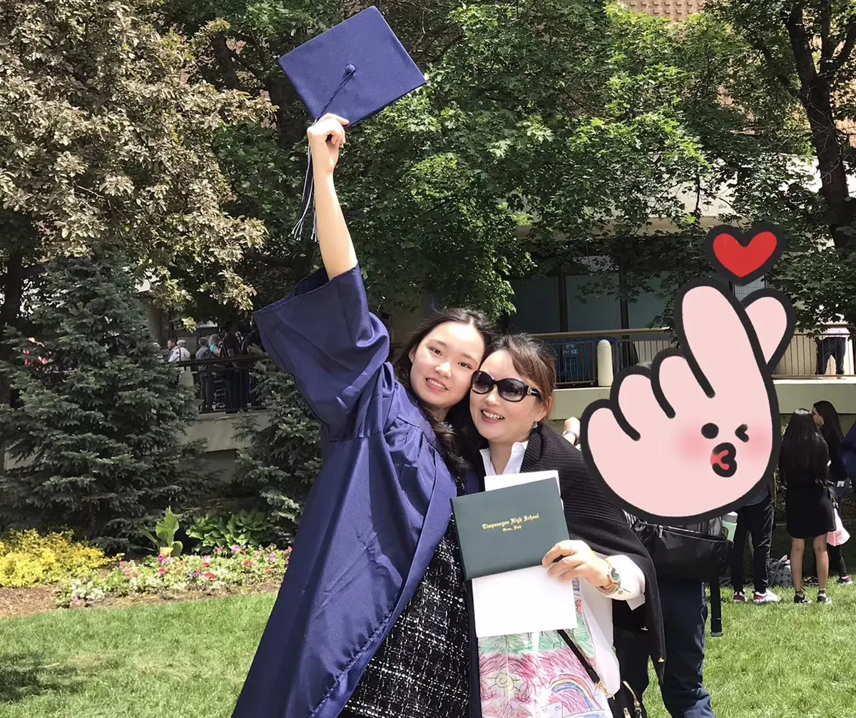 中国学生穿美国高中毕业服与同伴庆祝毕业