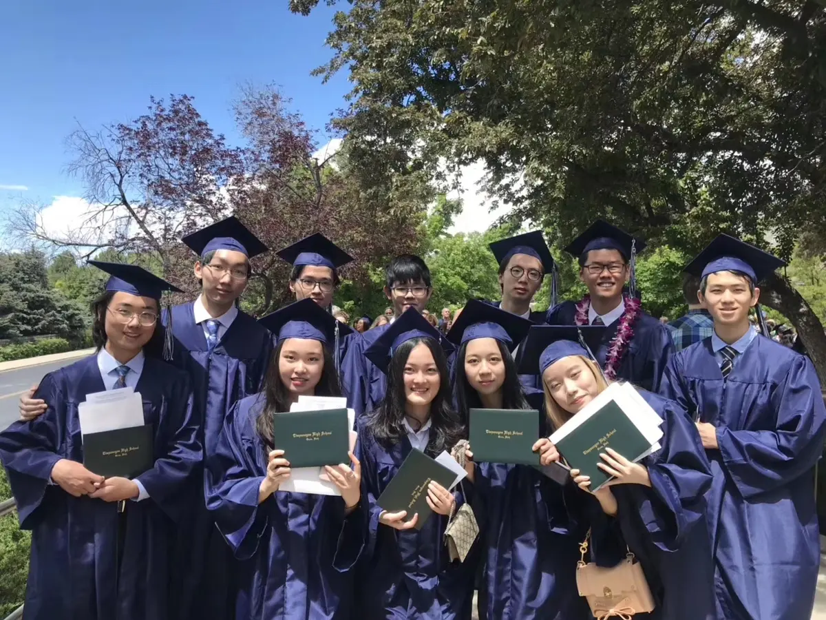中国学生身着毕业服在美国高中毕业典礼现场集体合影