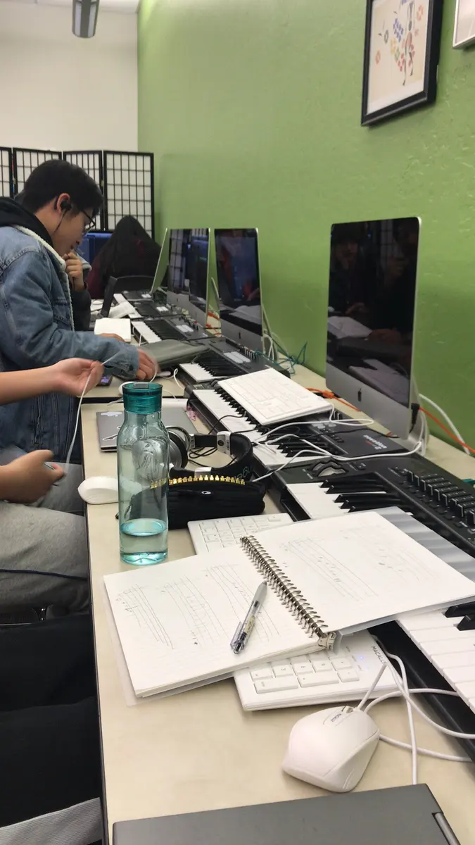 学生在MIDI音乐编曲课程中操作键盘与电脑