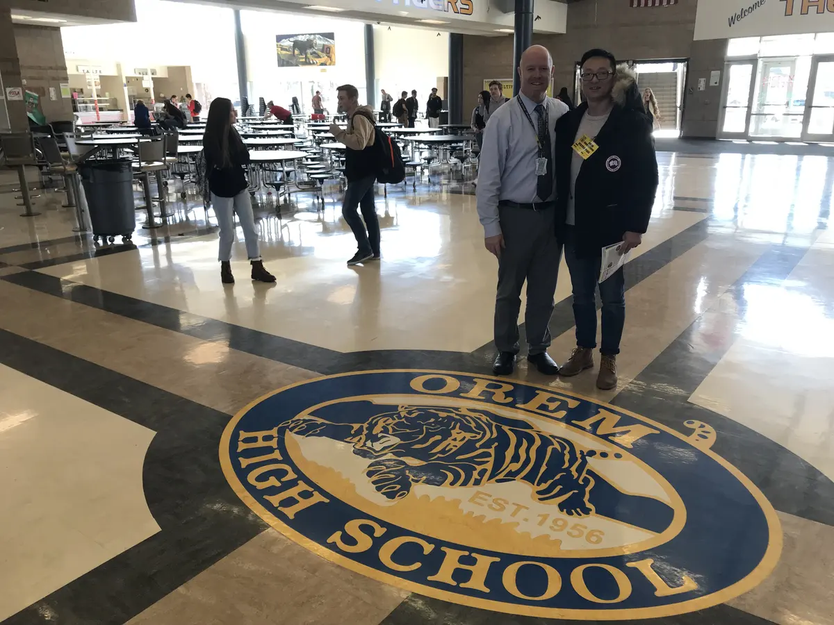 项目人员与学校代表在 Orem High School 校徽前合影