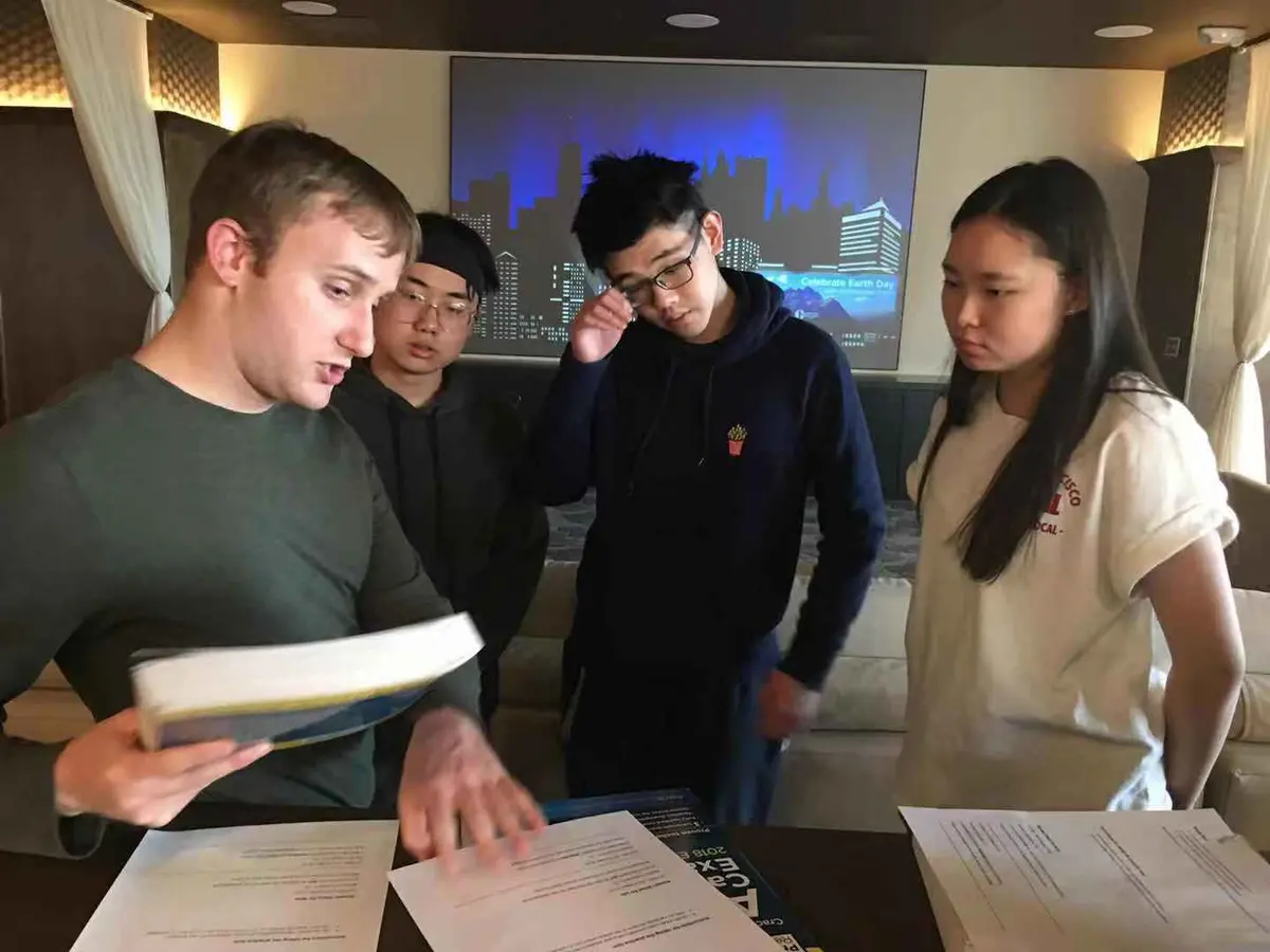 中美学生在室内围绕学习材料开展小组讨论