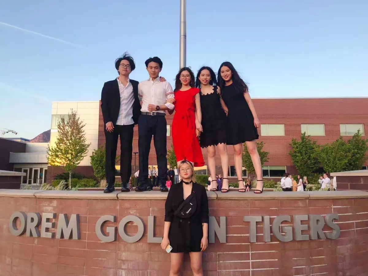 中外学生在 Orem High School 校名墙前参加正式活动合影