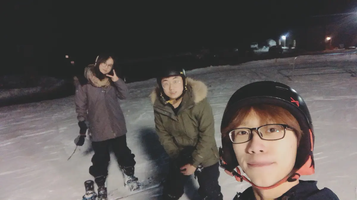 学生在夜间雪场参加滑雪活动并自拍