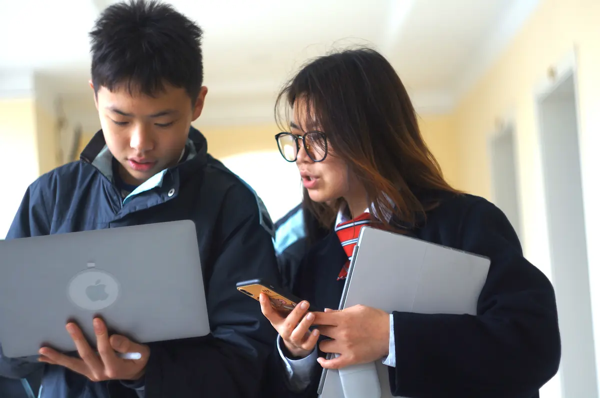 两名学生携带电脑和学习资料参加双向课堂活动