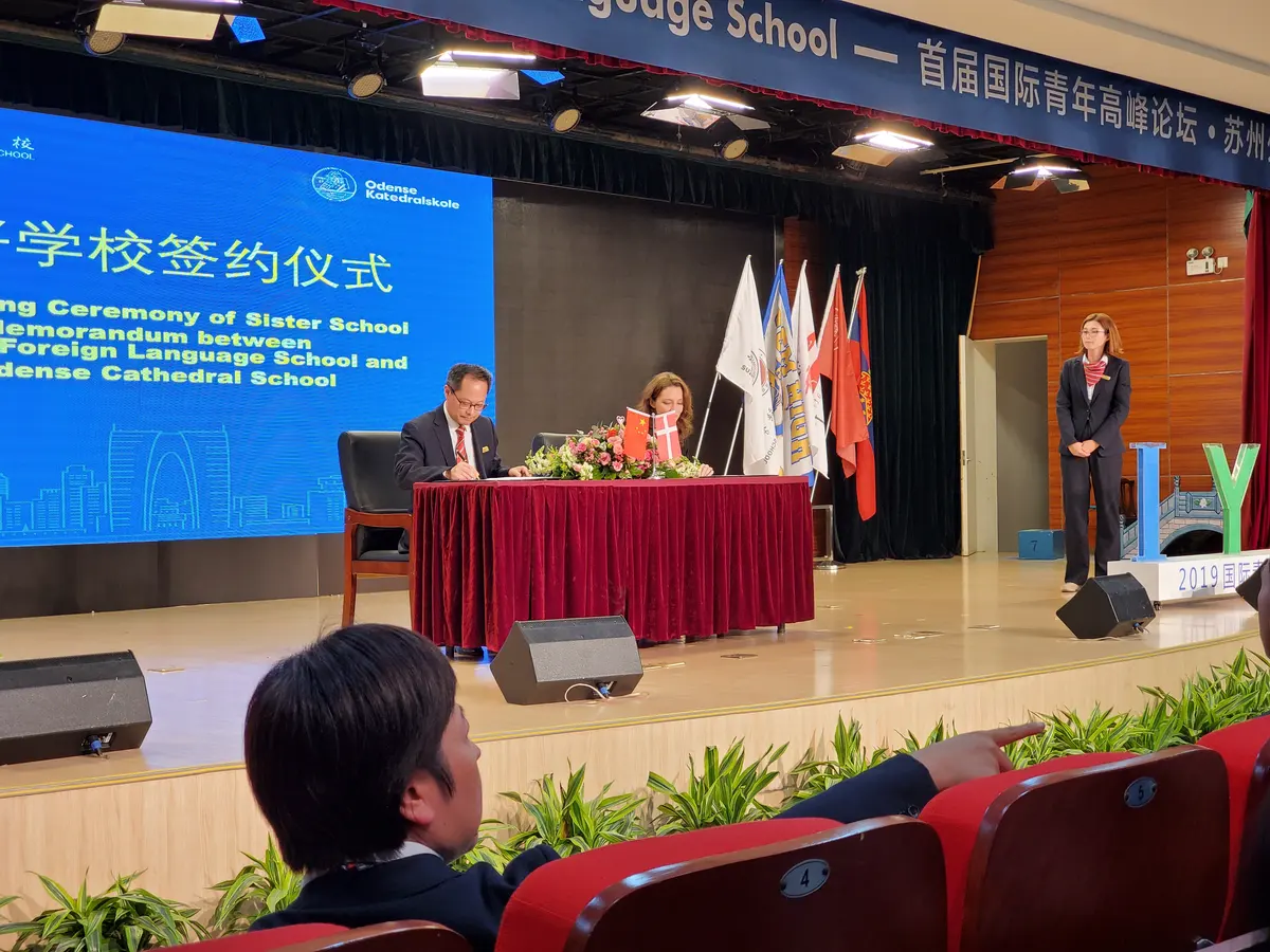中美学校合作签约仪式现场，嘉宾在舞台签署合作文件