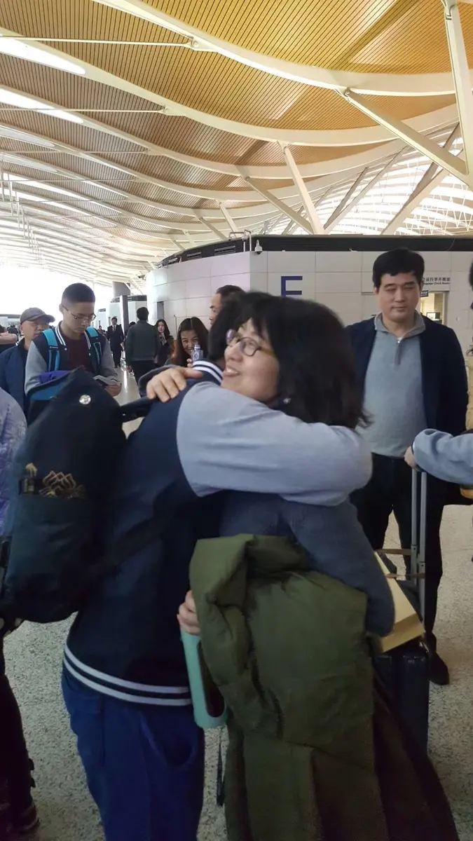 学生抵达机场后与家人或接待人员拥抱