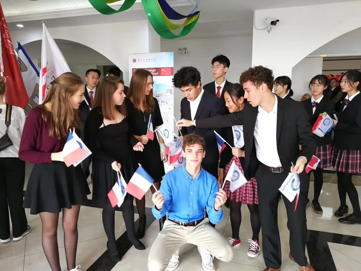 中外青年学生在国际青年峰会现场交流并展示各国旗帜