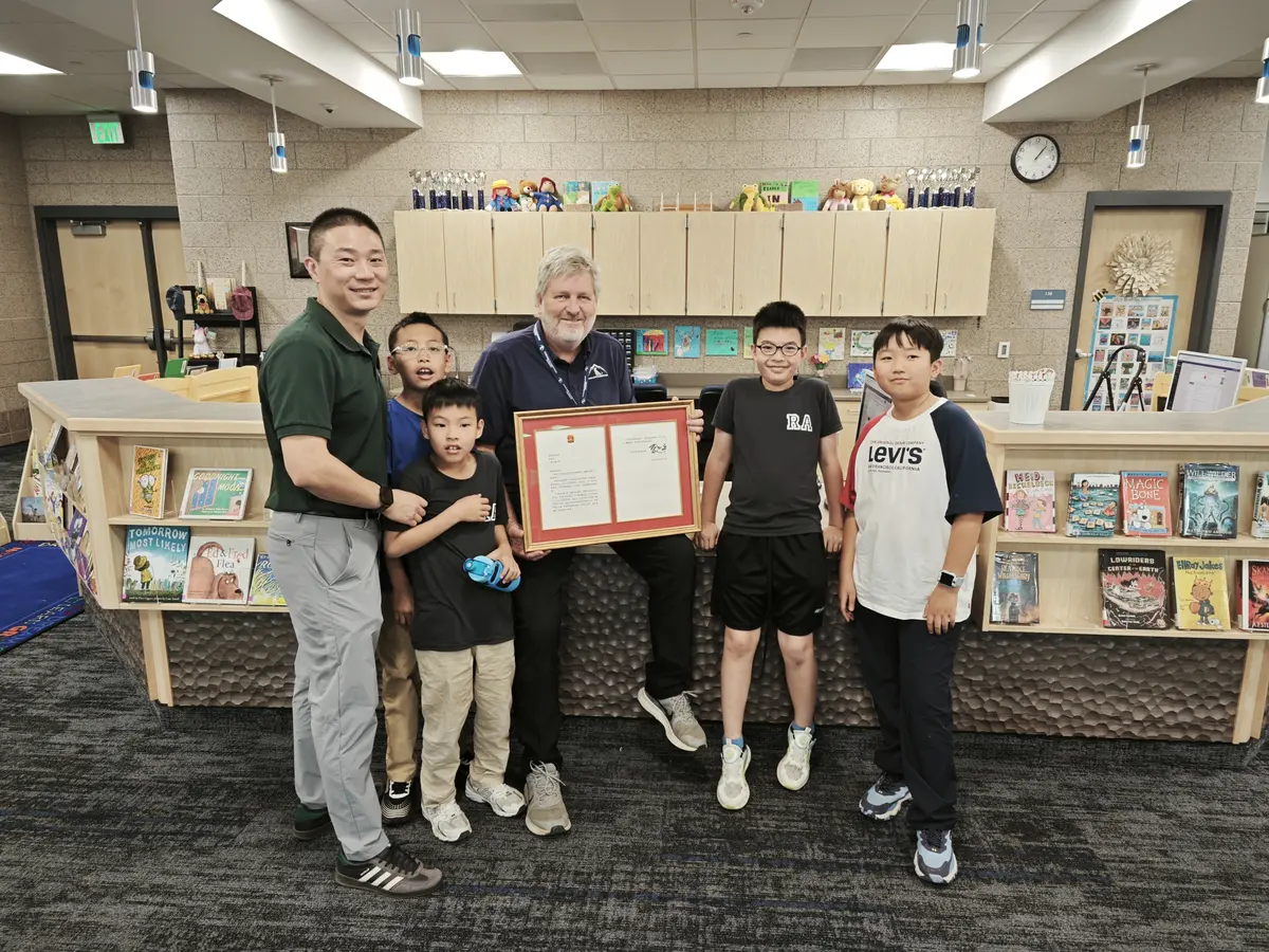 中国学生家庭与美国教师或合作方代表在学校内合影并展示纪念证书